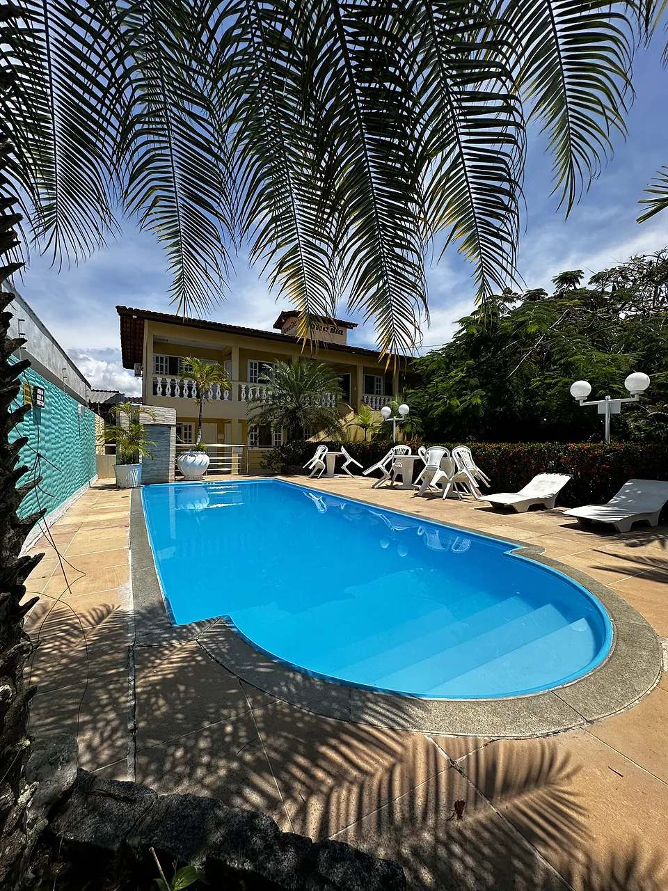 Piscina azul cercada por espreguiçadeiras e palmeiras